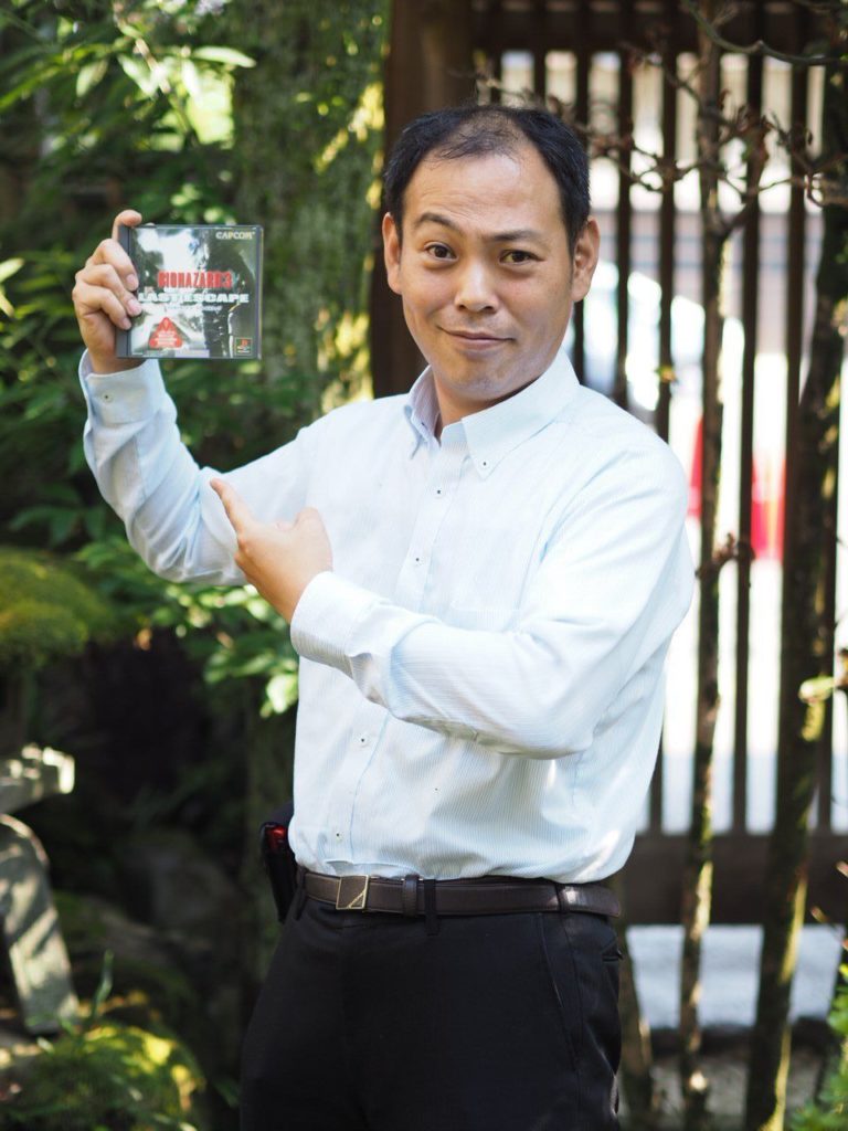 Photo of Kazuhiro Aoyama holding a copy of Resident Evil 3